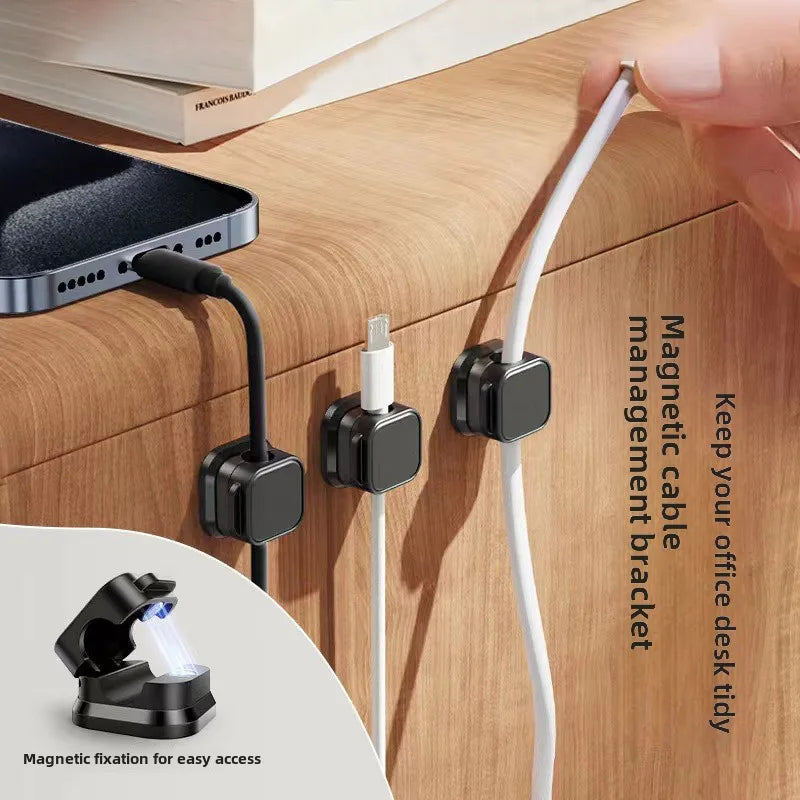 hand docking a white charging cable into a hinged magnetic cable dock fixed to the table lip with row of magnetic cable docks mounted along a wood desk lip