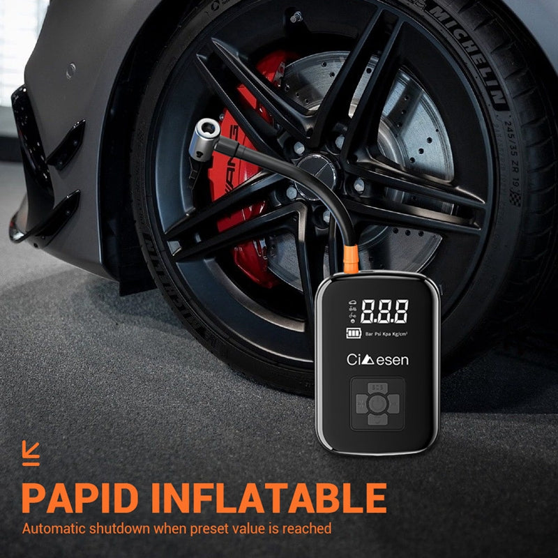 Close-up of portable air pump inflating a car tire with brake caliper and wheel detail.