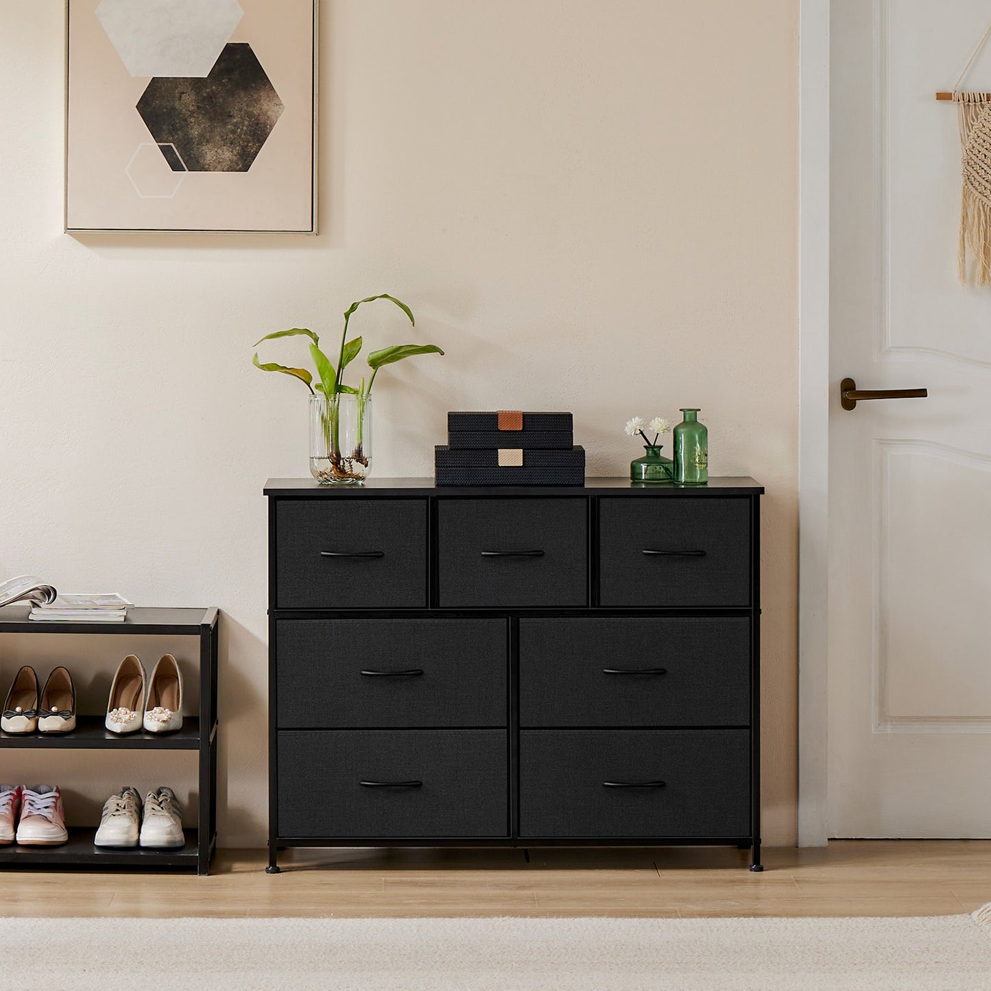 Black 7-drawer fabric dresser placed in modern entryway, styled with decorative plants and boxes
