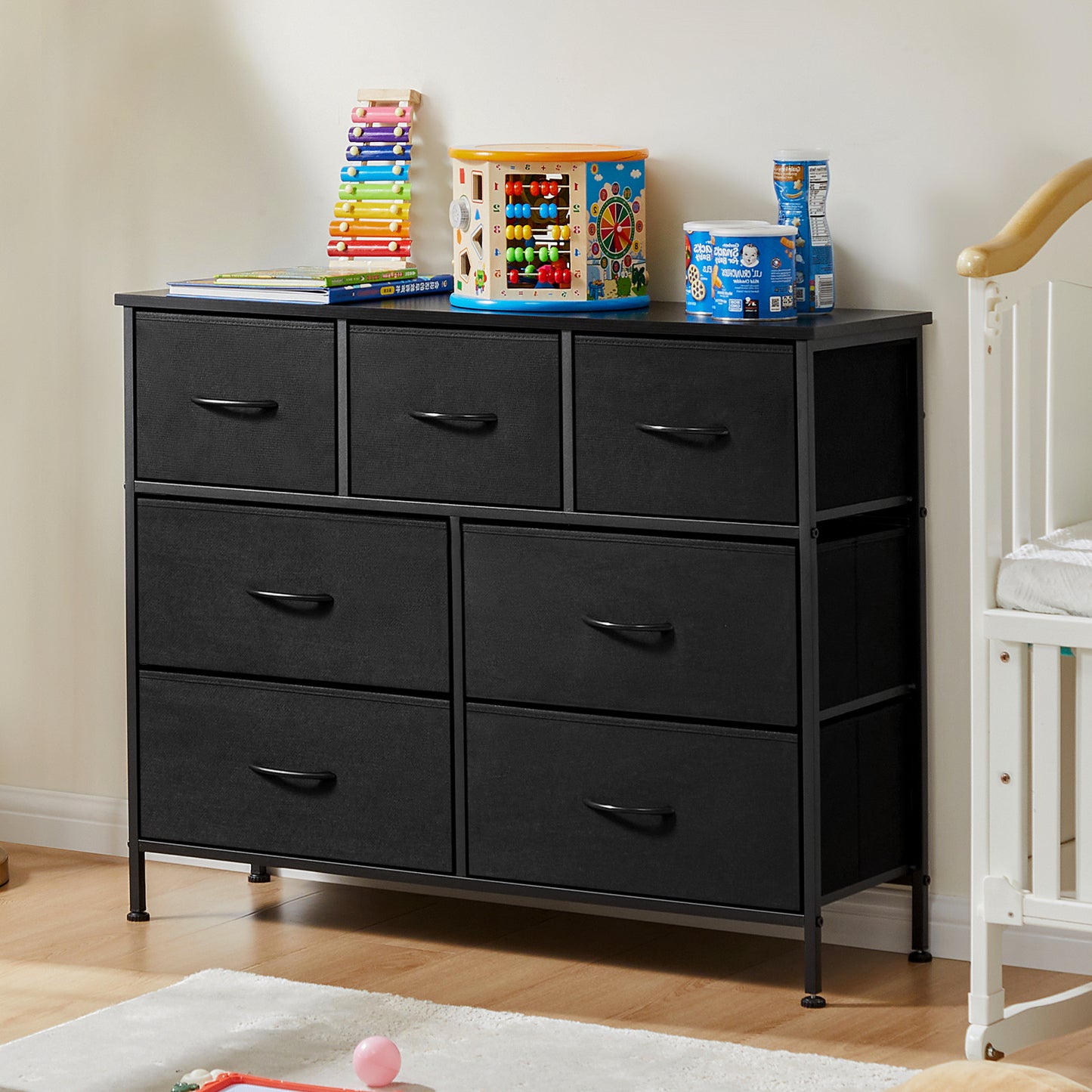 Black fabric dresser with 7 drawers in nursery room setting, topped with toys and storage items