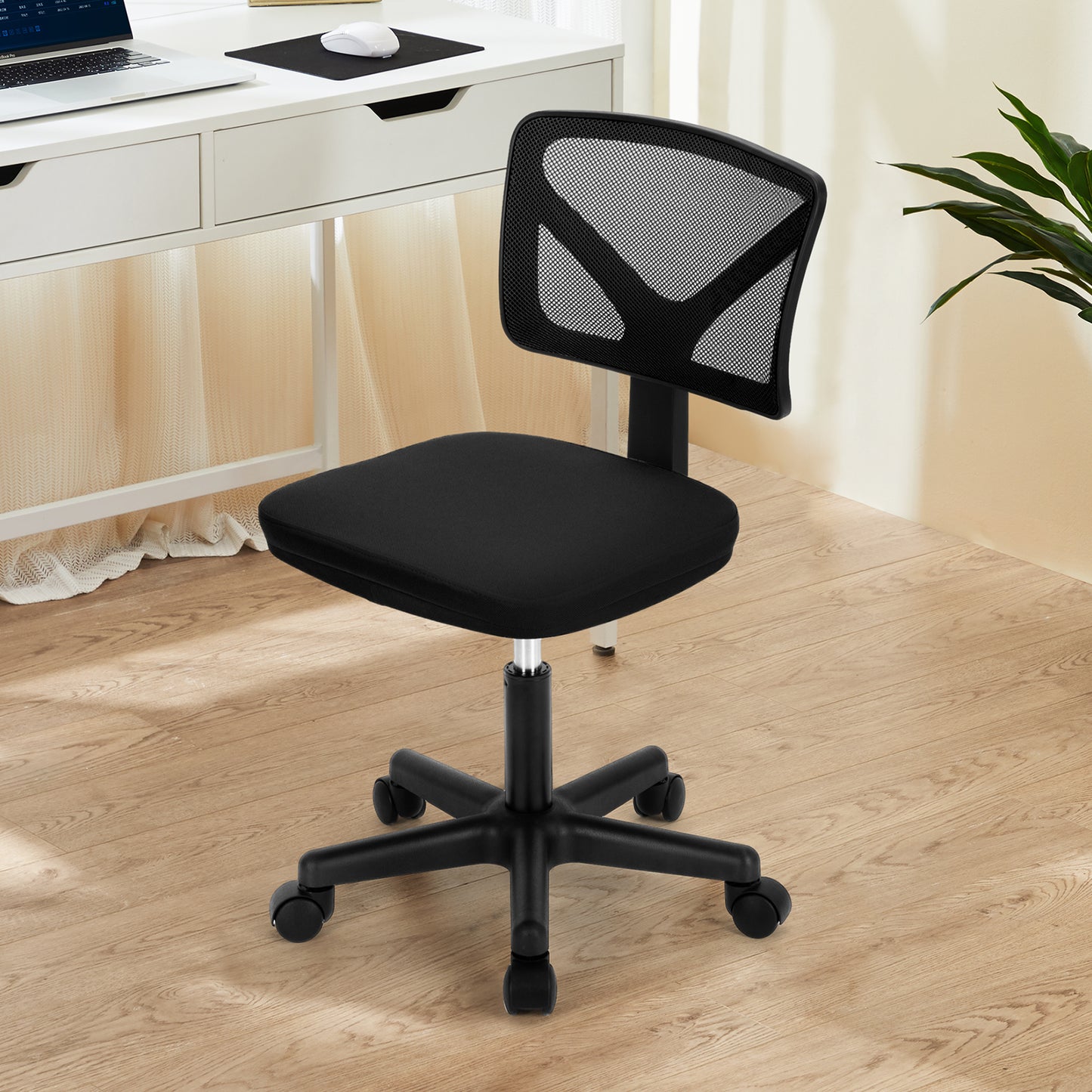 Black mesh office chair in front of a white desk with natural light in background