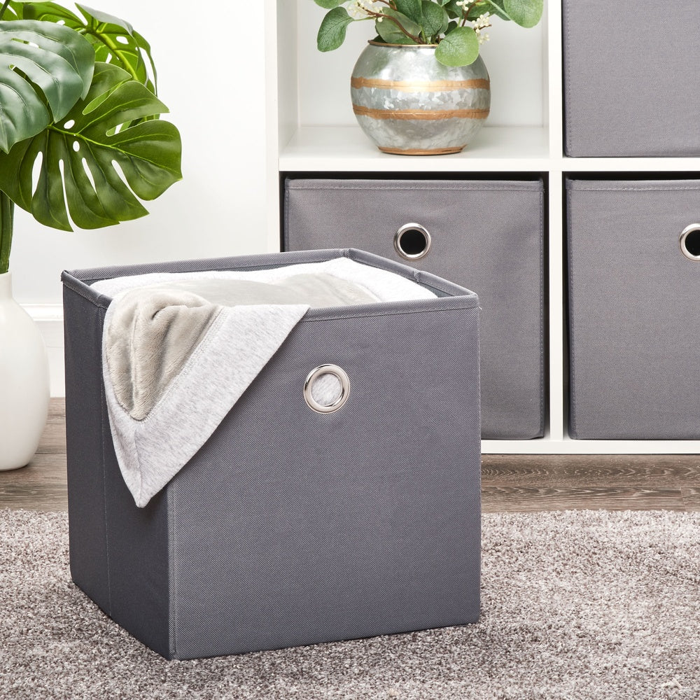 Gray collapsible fabric storage bin with blanket inside, placed in living room setup