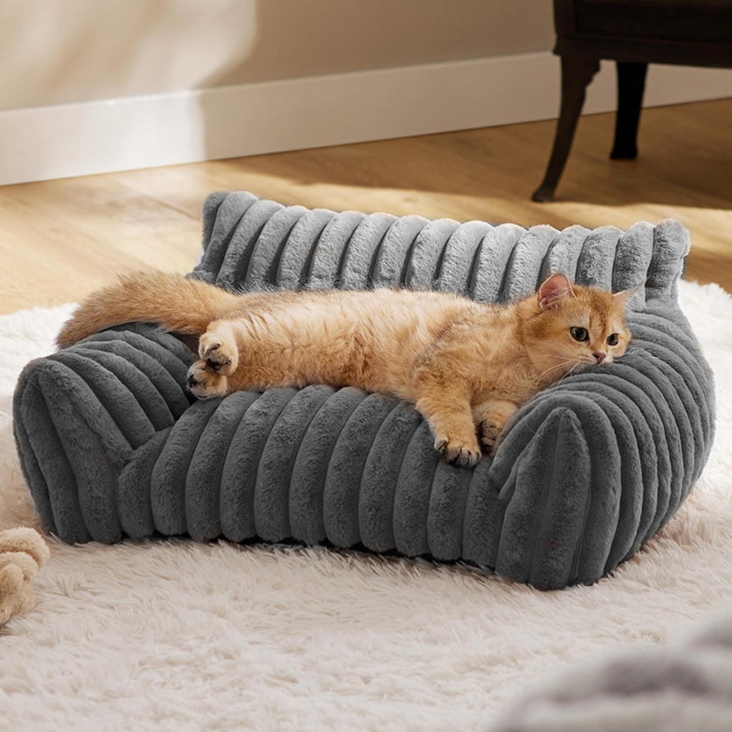 Cat lying on a gray armchair shaped pet bed in a cozy home setting