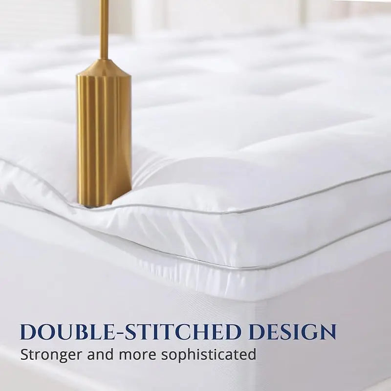 Close-up of mattress topper corner showing double-stitched edge on white fabric