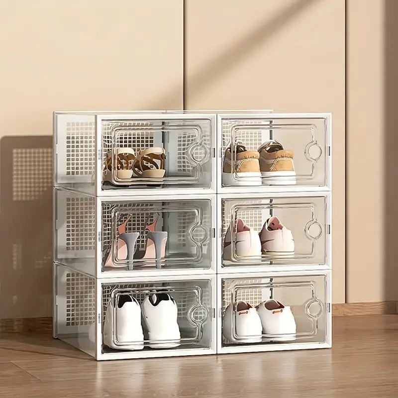 White stackable transparent shoe storage boxes filled with various shoes in a beige room setting with natural lighting.