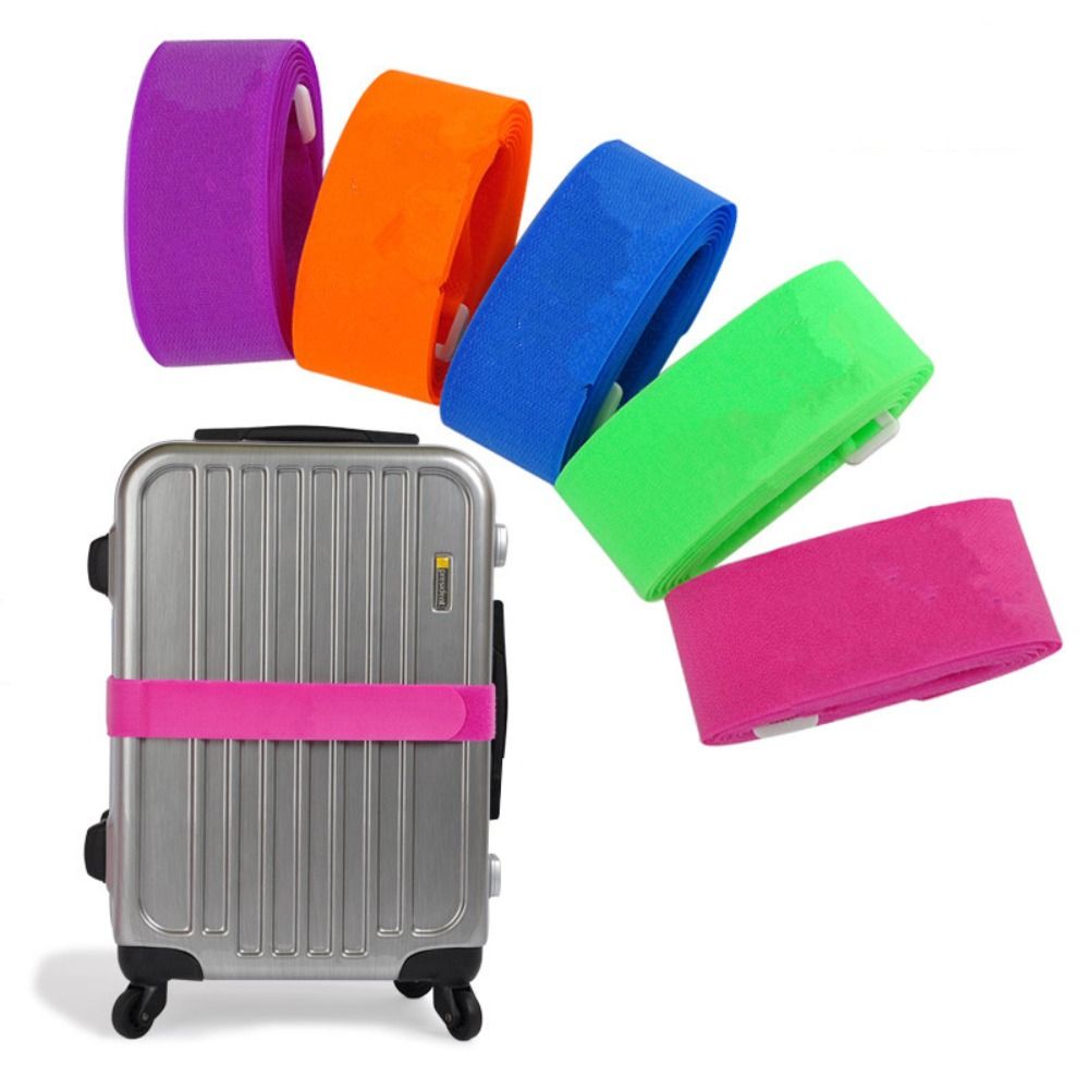 Pink luggage strap wrapped around silver suitcase, with additional straps in orange, blue, green, and purple shown.
