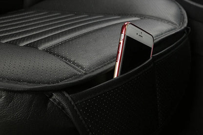 angled view of a black backless car seat cushion; perforated leatherette surface and a slim side pocket with a phone partially inserted