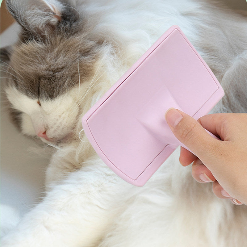 Pink grooming brush being used on a fluffy white and grey cat