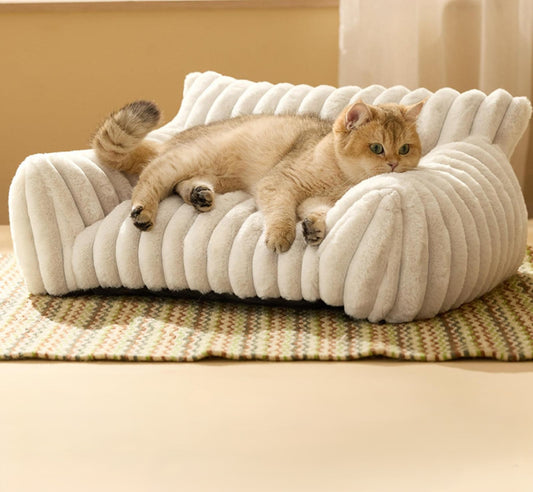 Cat lying on a plush, white pet bed in a cozy room.