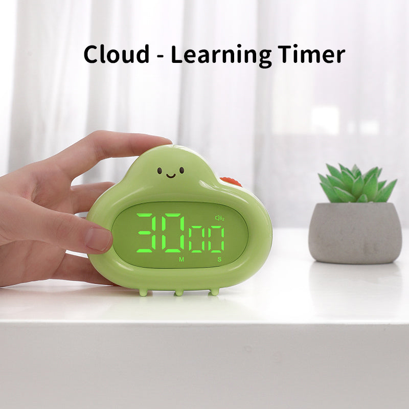 A person’s hand is shown holding the green cloud timer on a white desk. The LED display reads “30:00,” and the text “Cloud – Learning Timer” appears above the product. A small green succulent plant is blurred in the background.