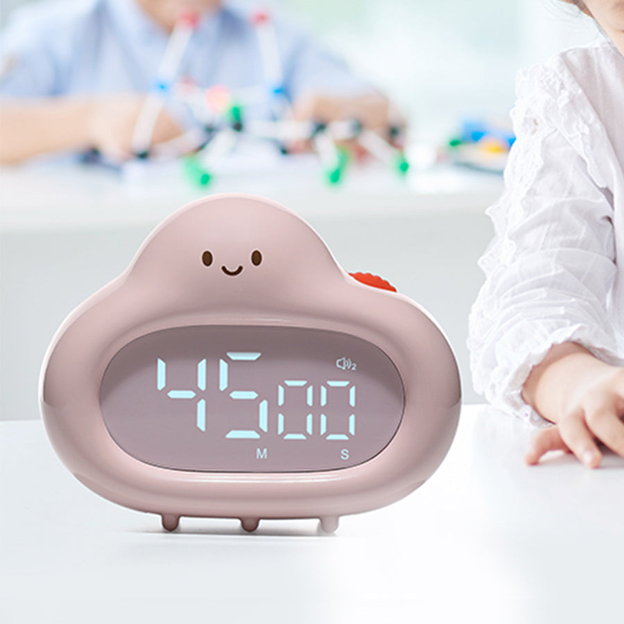 A pink cloud timer placed on a white desk, with its LED screen displaying “45:00.” A child’s arm and school materials are visible in the background, suggesting the timer is being used for focused study or classroom sessions.