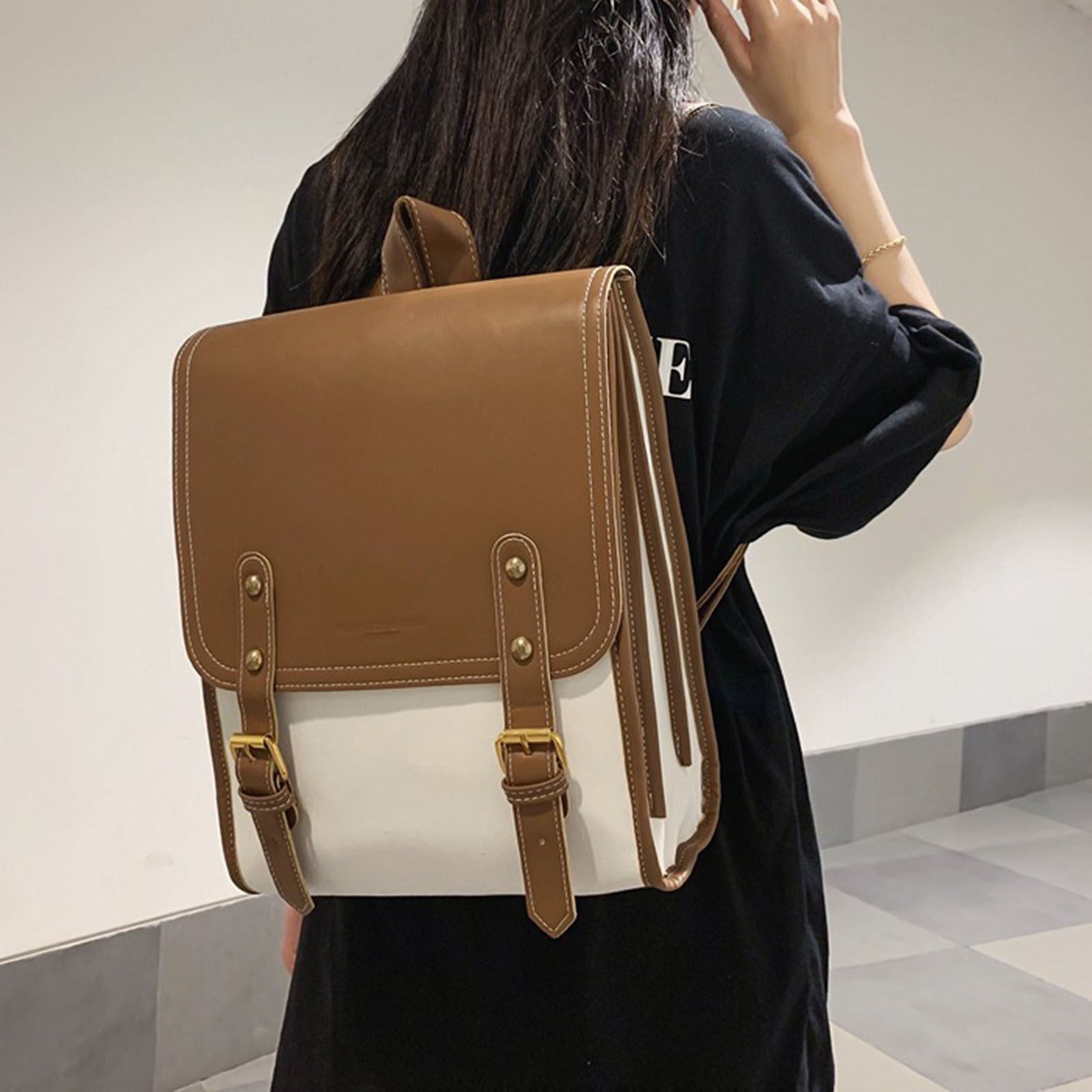 Lifestyle image of a woman wearing the brown and white backpack over one shoulder, highlighting its fashion-forward and wearable style.