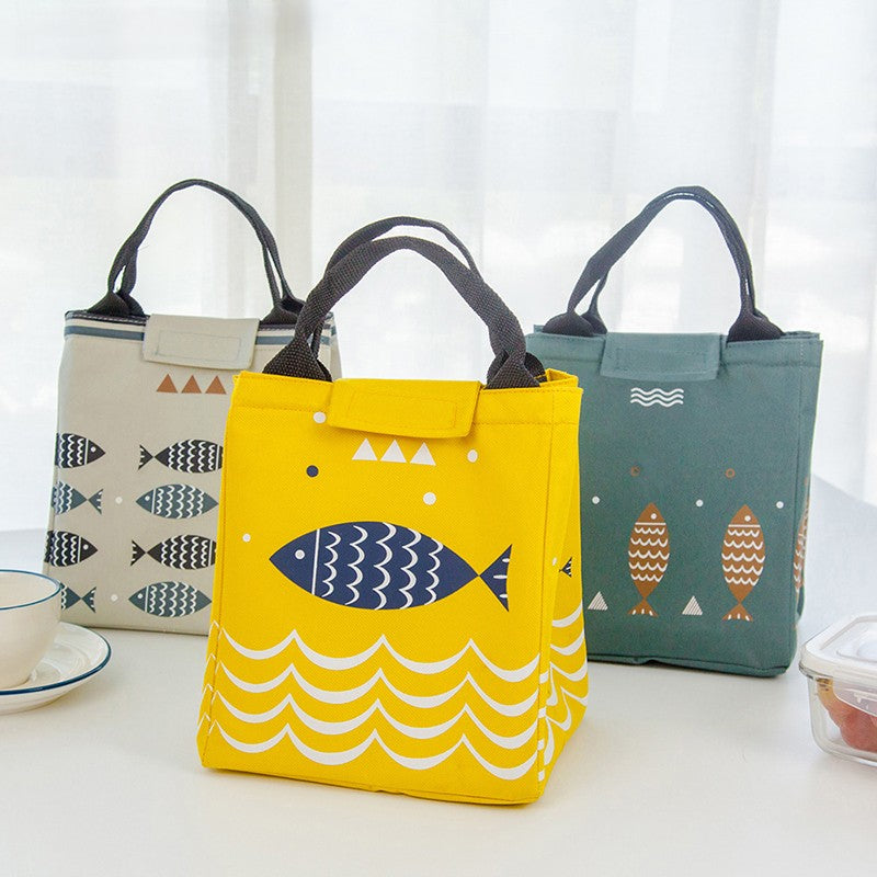 Three colorful insulated lunch bags standing on a white table.