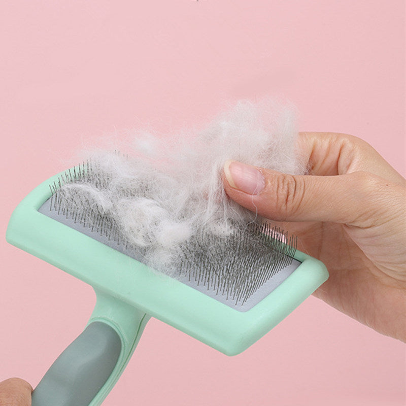 Hand removing pet hair from green slicker brush filled with white fur