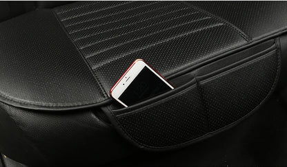 close-up of a black perforated leatherette car seat cushion with ribbed center panels, showing an integrated side storage pocket holding a smartphone