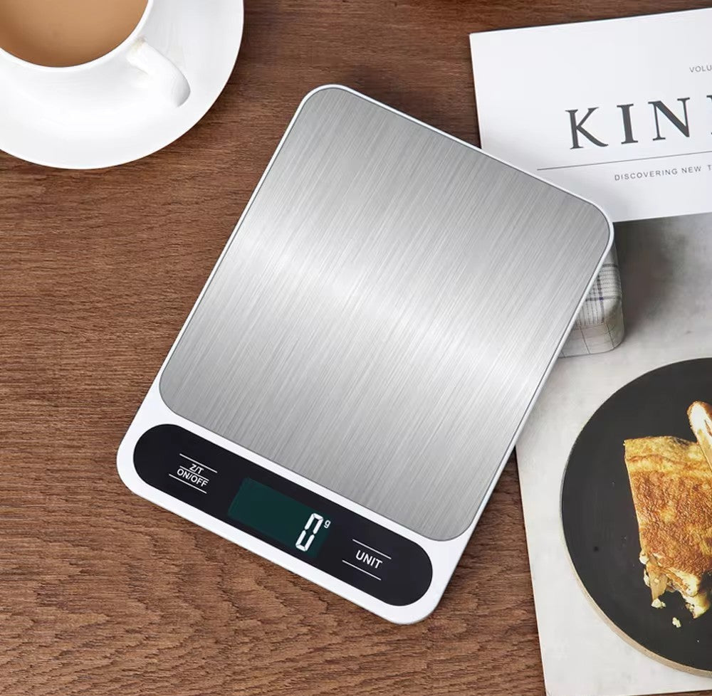Top view of white stainless steel kitchen scale on wooden table.