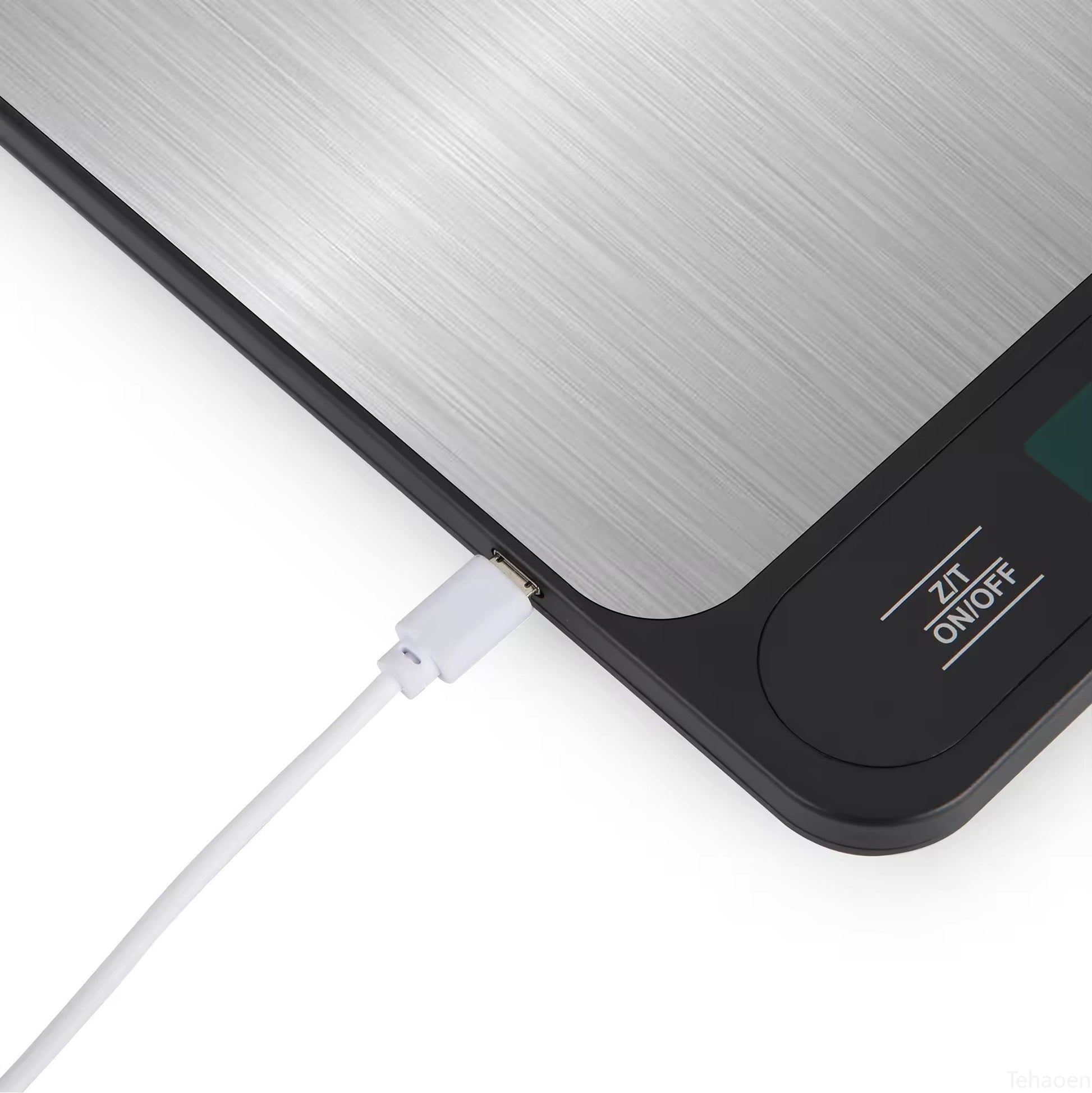 Close-up of USB charging cable connected to digital kitchen scale port.