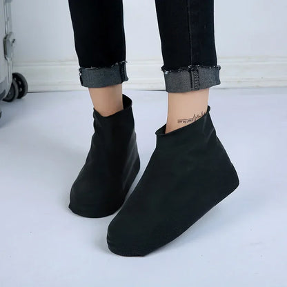 Black silicone shoe covers on feet standing indoors
