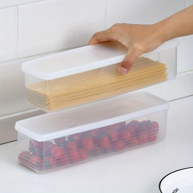 Two transparent food storage containers with white lids are placed on a clean white kitchen countertop. One hand is seen placing a container filled with spaghetti on top of another filled with cherry tomatoes, showcasing stackability and space-saving design.
