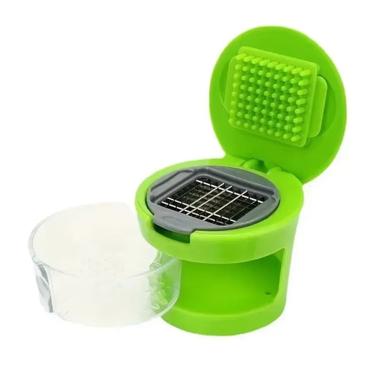 Disassembled green garlic press with transparent collection cup and visible grid blade