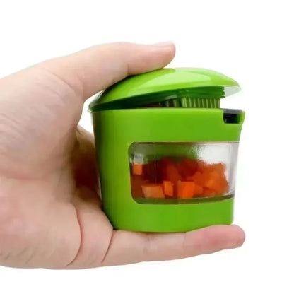 Compact green garlic press and dicer held in hand, showcasing its small and ergonomic design