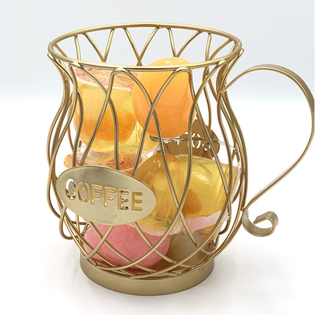 A gold iron wire coffee capsule holder filled with assorted dessert cups and orange jelly pods, photographed against a soft white background to highlight the basket's spacious interior.