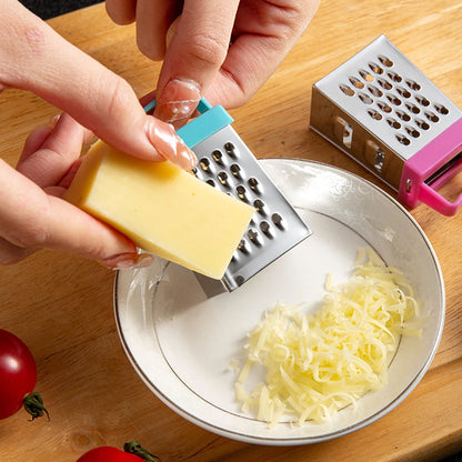Close-up of a hand using a mini stainless steel box grater with blue handle to grate cheese into a bowl