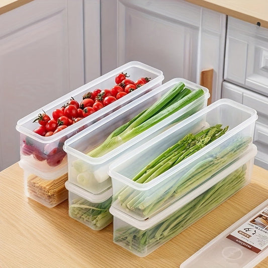 A set of six clear long rectangular food storage containers stacked on a kitchen counter, filled with fresh ingredients including cherry tomatoes, grapes, scallions, green onions, and asparagus. The containers are transparent with white lids and are arranged to show their stackable design.