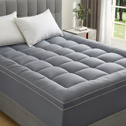 Quilted gray mattress topper fitted on bed in bright bedroom