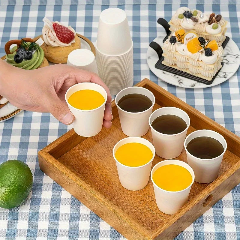 White paper cups filled with juice and coffee on a wooden tray with desserts.