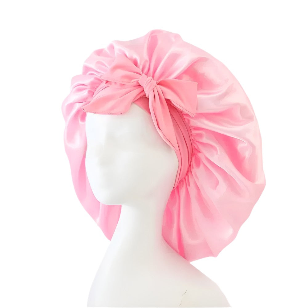 Pink satin bonnet styled with bow on white mannequin head