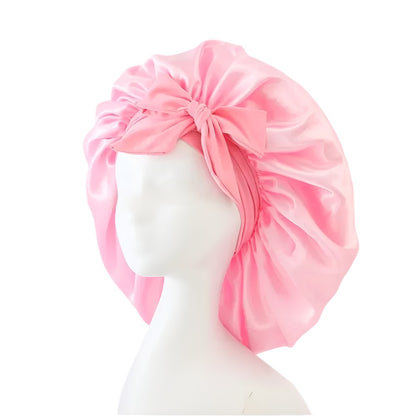 Pink satin bonnet styled with bow on white mannequin head