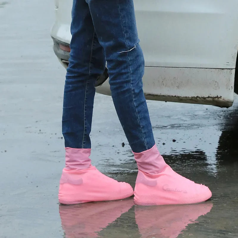 Person wearing pink shoe covers walking on wet pavement