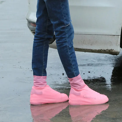 Person wearing pink shoe covers walking on wet pavement
