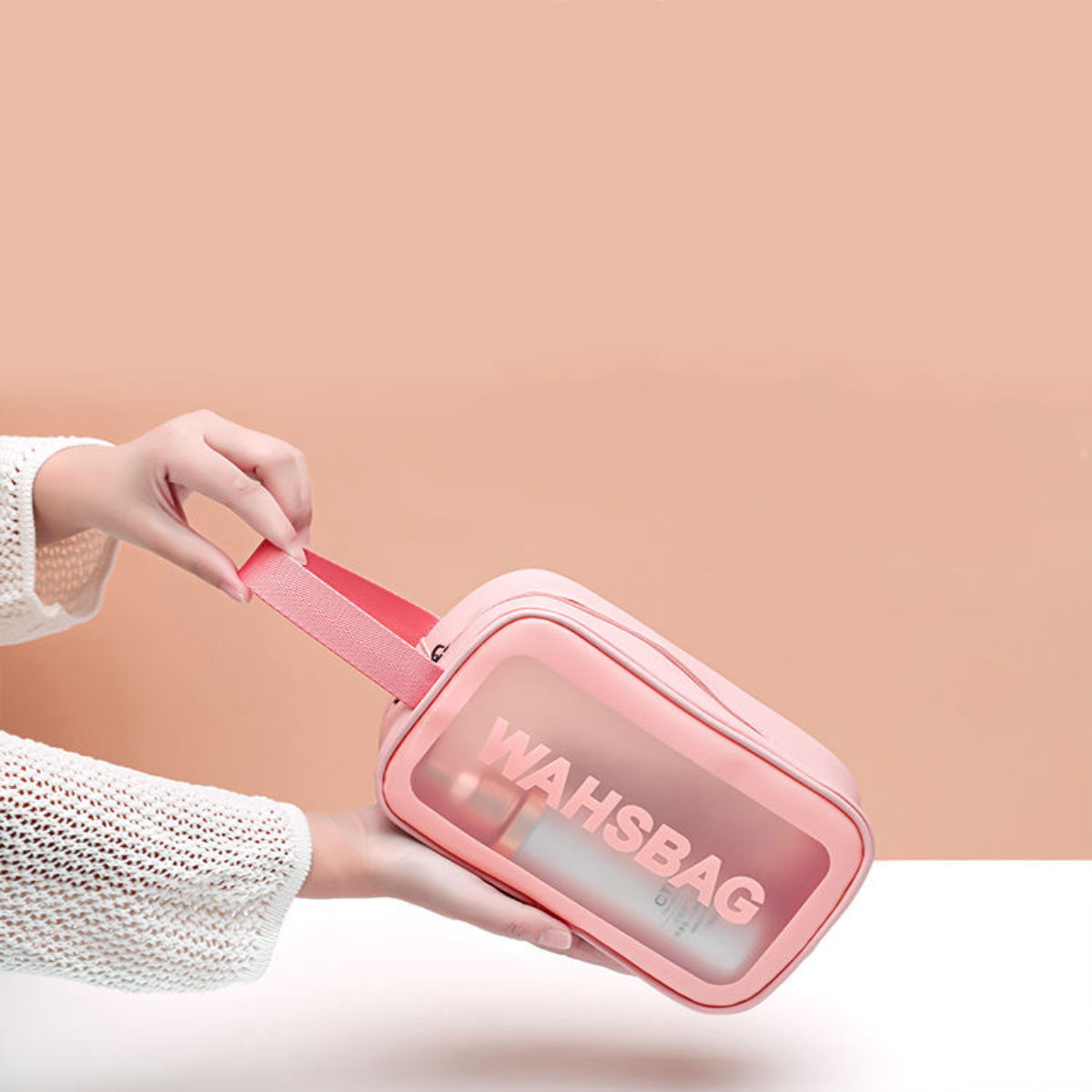 Hand holding the pink washbag by its sturdy fabric handle, demonstrating the portability of the travel-friendly makeup bag.