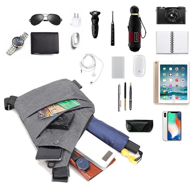 Gray crossbody sling bag displayed with common daily items including phone, wallet, camera, tablet, pen, charger, watch, and umbrella to show maximum storage potential.
