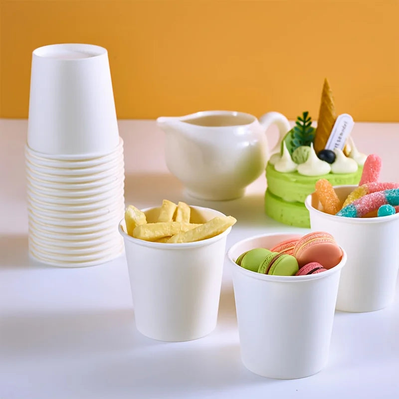 tacked white paper cups next to snacks and macarons with a yellow background.