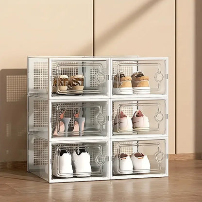 White stackable transparent shoe storage boxes filled with various shoes in a beige room setting with natural lighting.